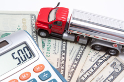 Image of calculator, money, and miniature long haul truck