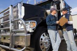 Image of customer and trucker reviewing documents beside the truck