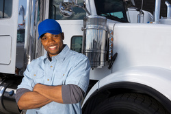 Image of smiling trucker in front of his long haul truck