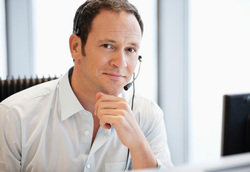 Image of executive at his desk with headphones on.